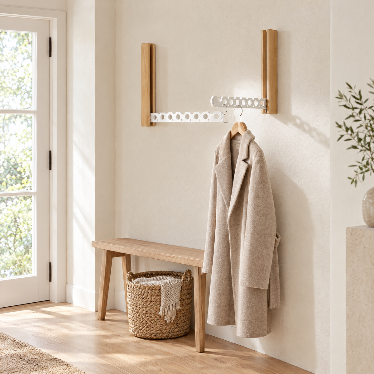 Piega Folding Wall Hanger Rail in white holding a coat in an entryway