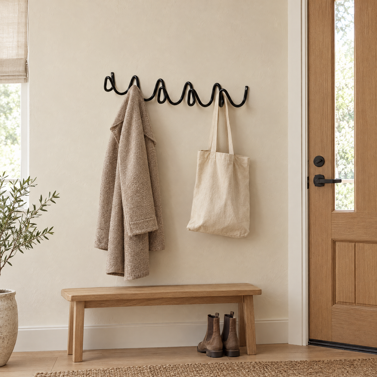 Flutto Wave Wall Hook Rack in black holding a coat by the front door