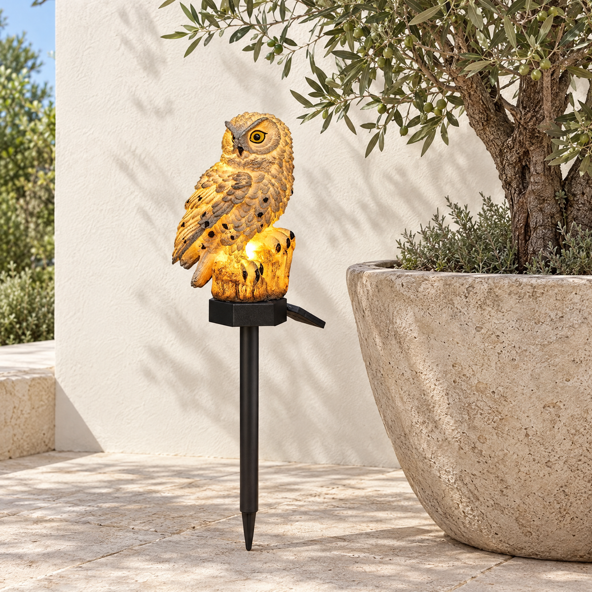 Gufo solar owl light beside an olive tree planter on a stone terrace