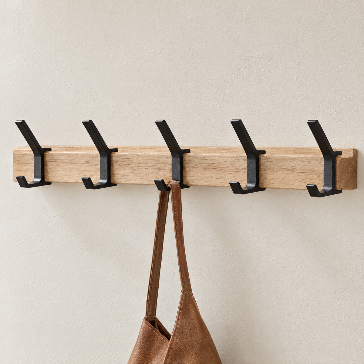 Close-up of the wood rail and black double hooks of Gancio