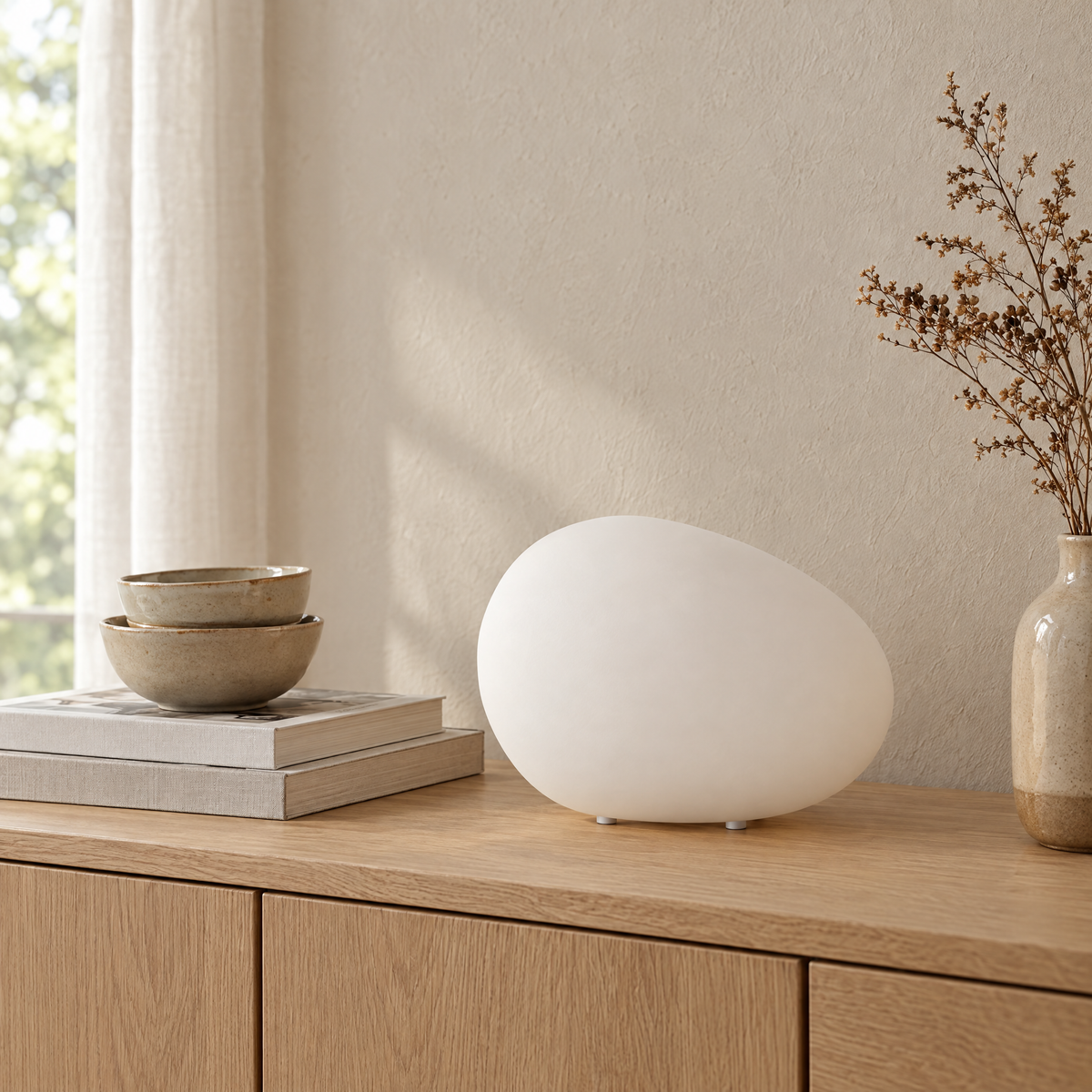 Ciottolo Pebble Bedside Lamp on a sideboard with ceramics